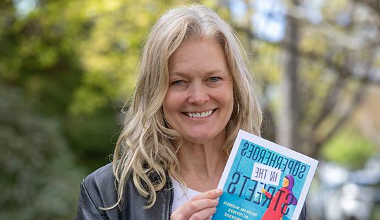 Professor Kimberly Wedeven Segall poses with her book Superheroes in the Streets